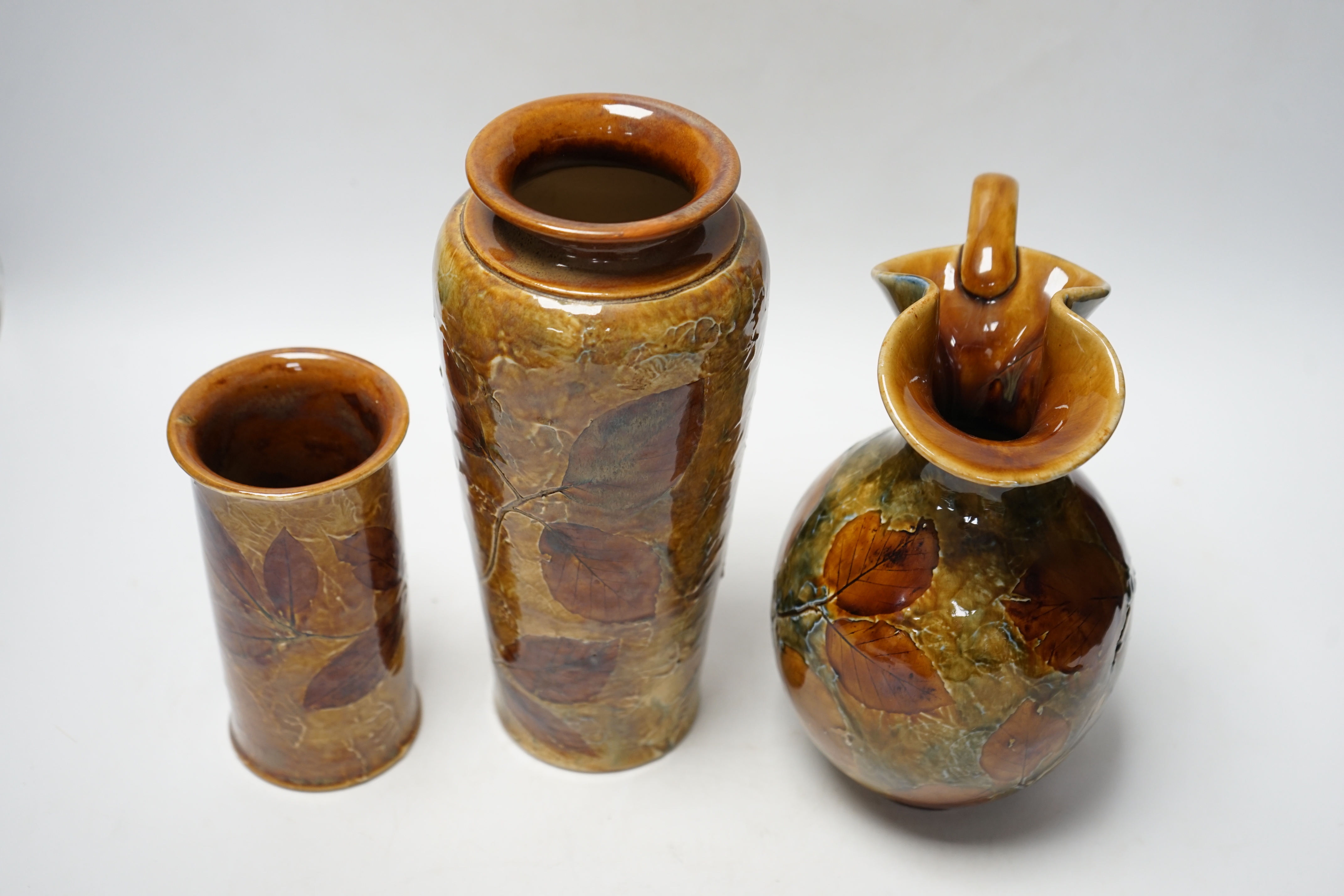 Two Doulton natural foliage ware vases and a jug, 25cm